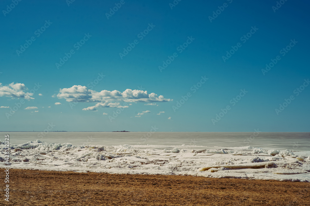 Finland gulf covered with ice and snow melting in April. Baltic beach on spring sunny day