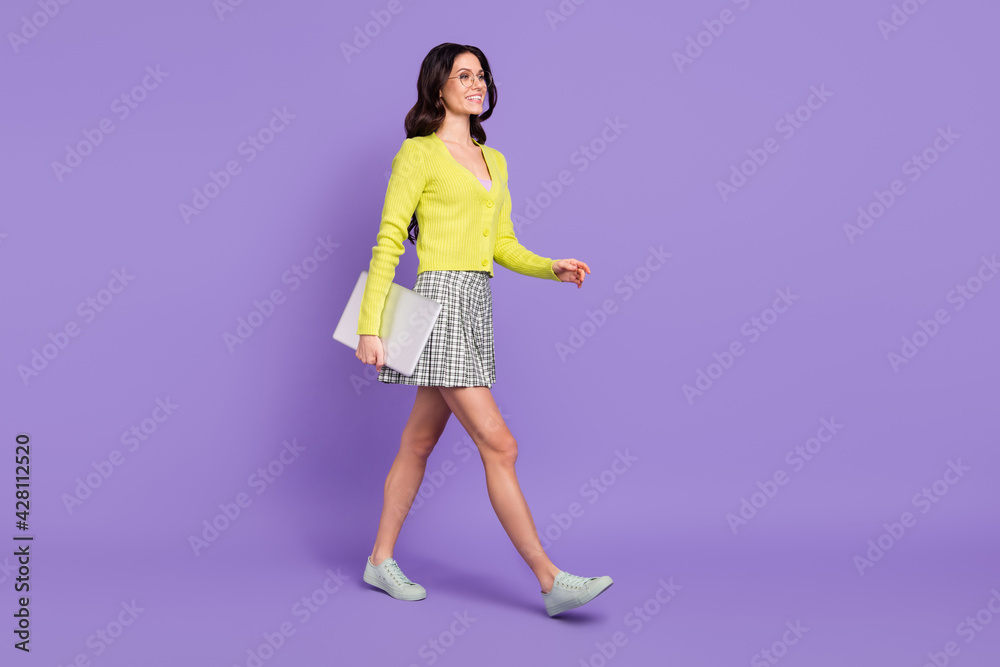 Full size profile photo of optimistic lady hold laptop go wear spectacles sweater skirt sneakers isolated on purple background