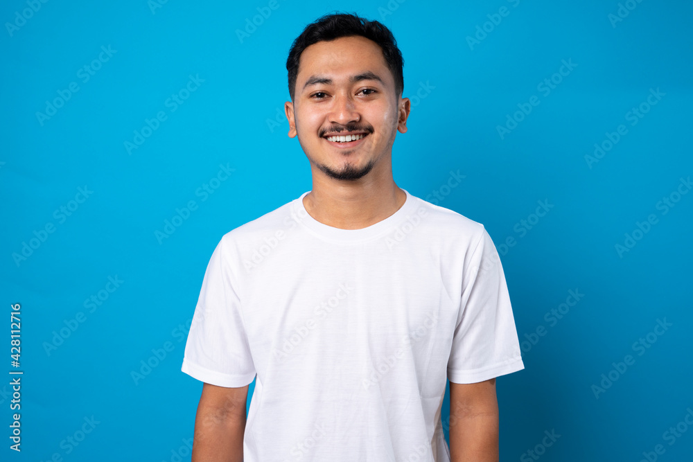 handsome young man with thin beard smiling confidently on blue background handsome young man with thin beard smiling confidently on blue background