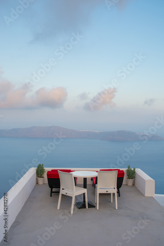 Volcano and caldera  view from a balcony in Imerovigli village, Santorini island, Greece. Clouds in the sky, nice day, calm sea