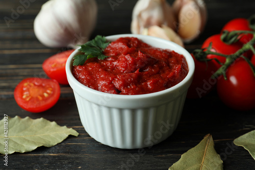Bowl with tomato paste, tomatoes and garlic on wooden table