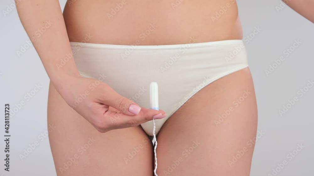 Young woman in lingerie holding hygienic tampon