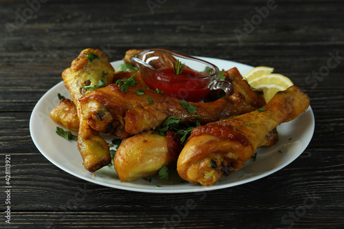 Concept of delicious eating with plate of roast chicken drumsticks on wooden background