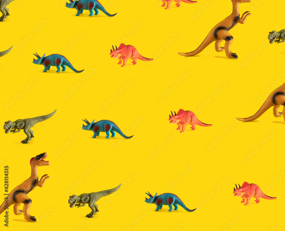 pattern made with dinosaur toy on yellow illuminating sunny background. abstract flat lay background pattern made with dinosaur toy on yellow illuminating sunny background. abstract flat lay background