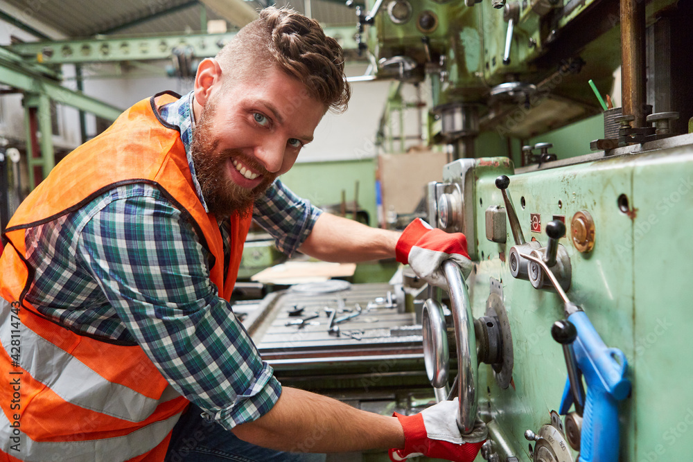 Arbeiter in Metallfabrik bedient Standbohrmaschine Arbeiter in Metallfabrik bedient Standbohrmaschine