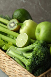 Basket with green vegetables on gray table
