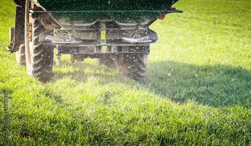 Foto Tractor spreading artificial fertilizers in field