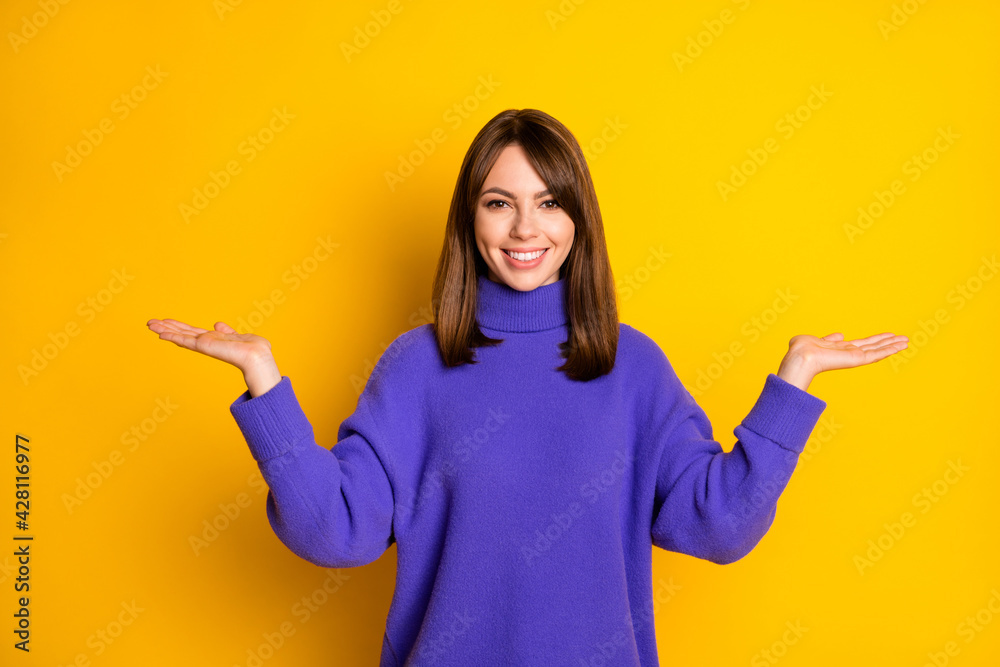 Photo of adorable pretty young lady dressed violet sweater showing scales holding empty space isolated yellow color background Photo of adorable pretty young lady dressed violet sweater showing scales holding empty space isolated yellow color background