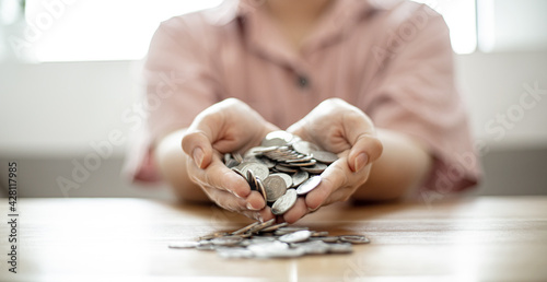 Women with two hands holding large amounts of coins are an expression of saving money, saving money for investment makes money grow. Concept of saving money and investing it to grow money.