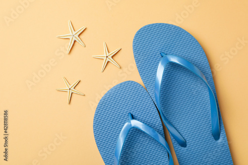 Blue flip flops and starfishes on beige background