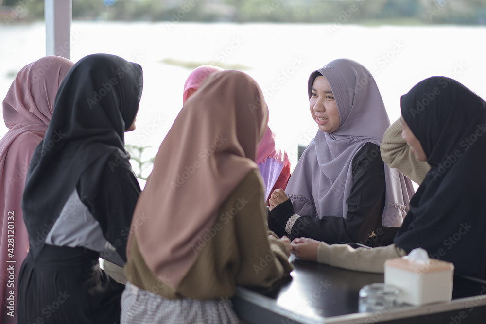 Group of young Muslim asian teenagers at cafe talking each other