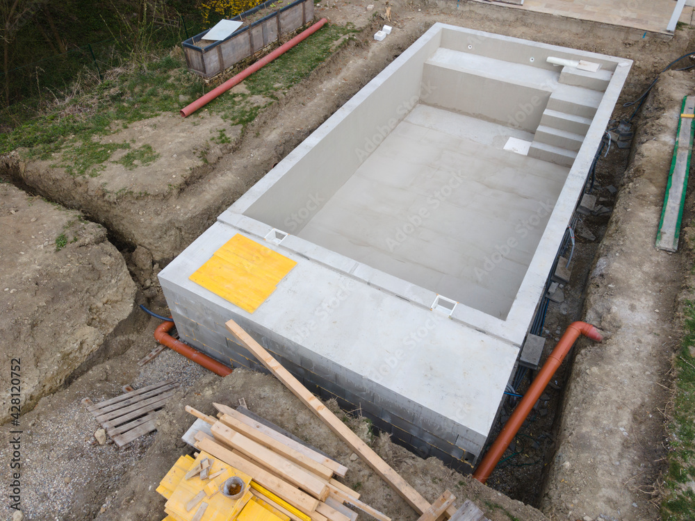 aerial drone shot of pool construction site almost finished spackling from above in a garden aerial drone shot of pool construction site almost finished spackling from above in a garden
