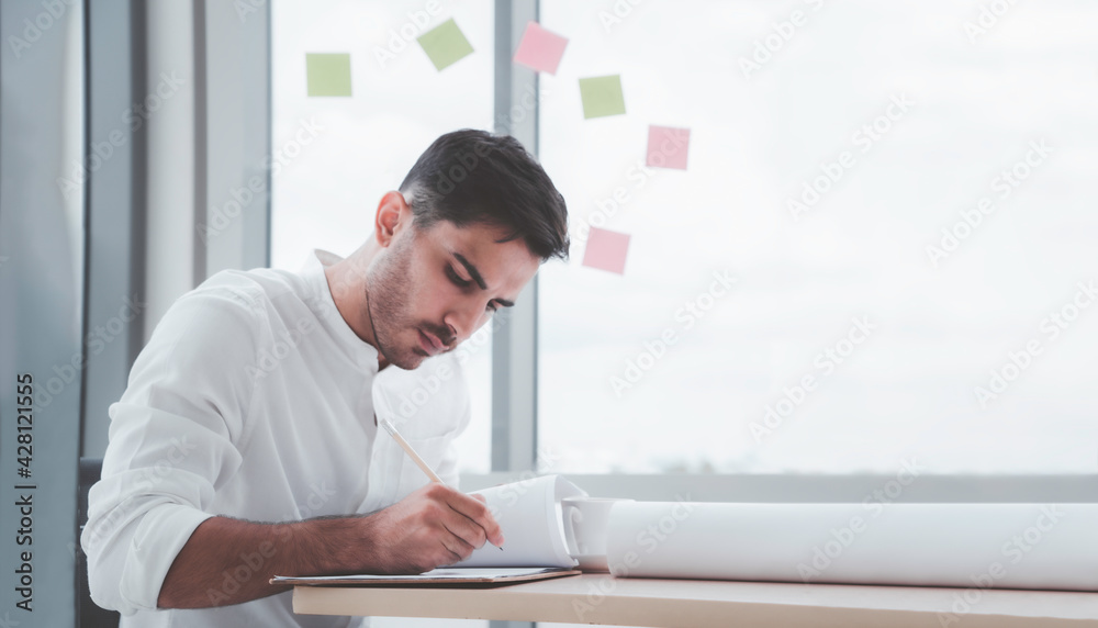 Engineering or architect beard male in white shirt concentrate writing working on paper at home office with copy space