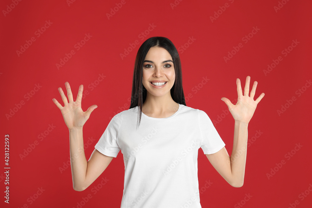 Woman showing number ten with her hands on red background Woman showing number ten with her hands on red background