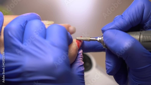 Closeup view 4k stock video footage of hands of woman undergoing beauty procedures in professional modern nailsalon. Manicurist doing manicure and polishing nails in pastel pink nude trendy color photo