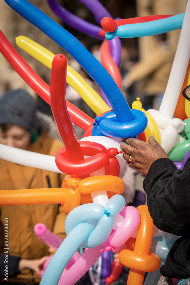 Closeup of a balloon seller with multi colored balloons in the shape of a sword and heart during the Carnival in Bologna city, Emilia Romagna, Italy, Europe. Closeup of a balloon seller with multi colored balloons in the shape of a sword and heart during the Carnival in Bologna city, Emilia Romagna, Italy, Europe.