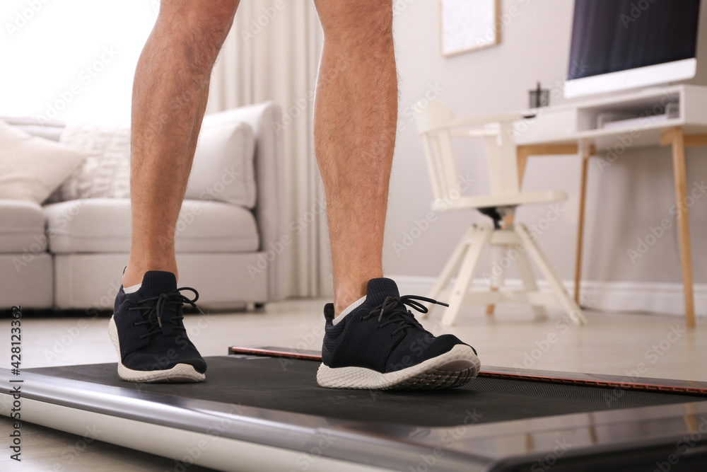 Man training on walking treadmill at home, closeup Man training on walking treadmill at home, closeup