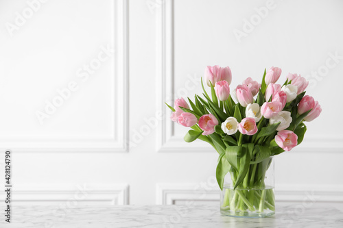 Fototapeta Naklejka Na Ścianę i Meble -  Beautiful bouquet of tulips in glass vase on white marble table. Space for text
