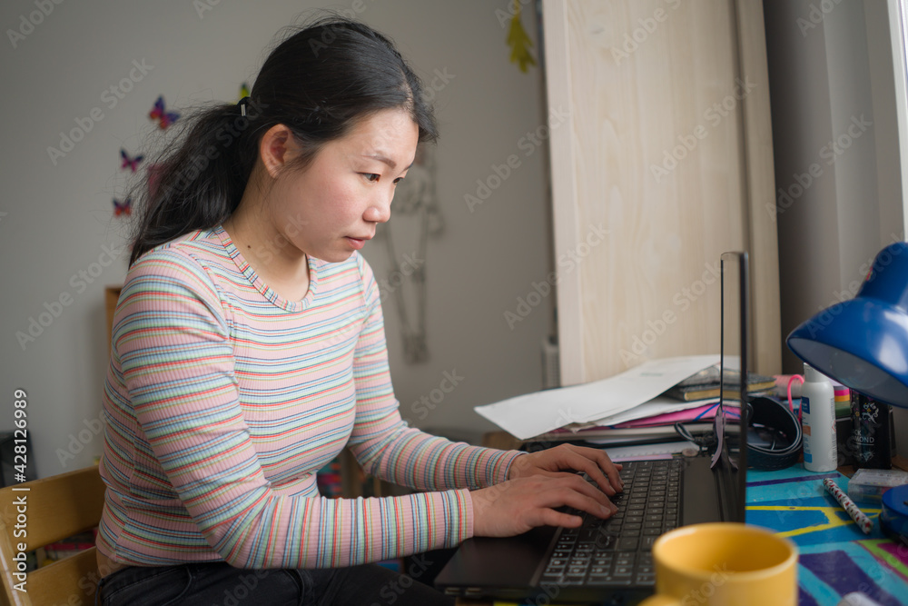 telework and remote job - lifestyle portrait of young happy and beautiful Asian Chinese woman working on laptop or studying at home office focused and relaxed