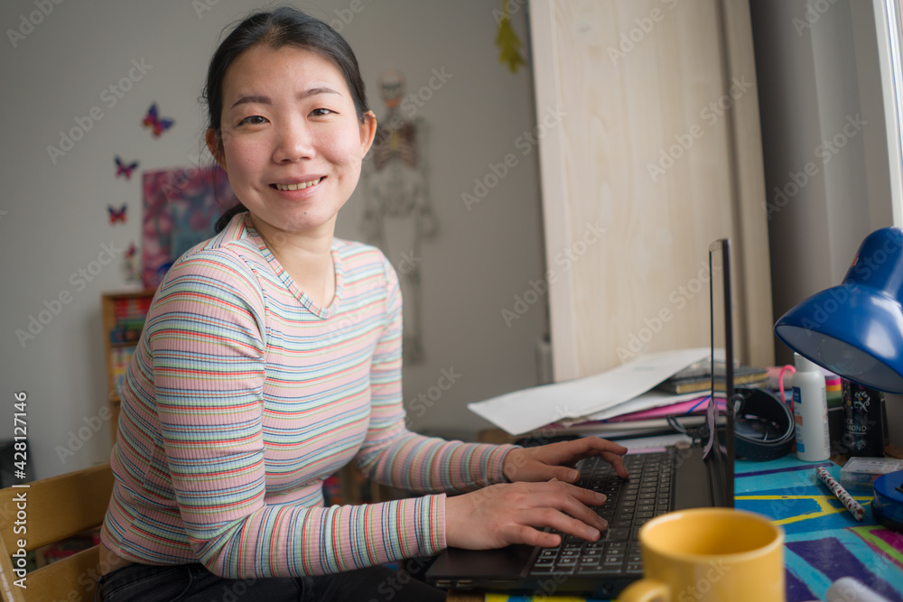 telework and remote job - lifestyle portrait of young happy and beautiful Asian Korean woman working on laptop at home office desk smiling cheerful and confident