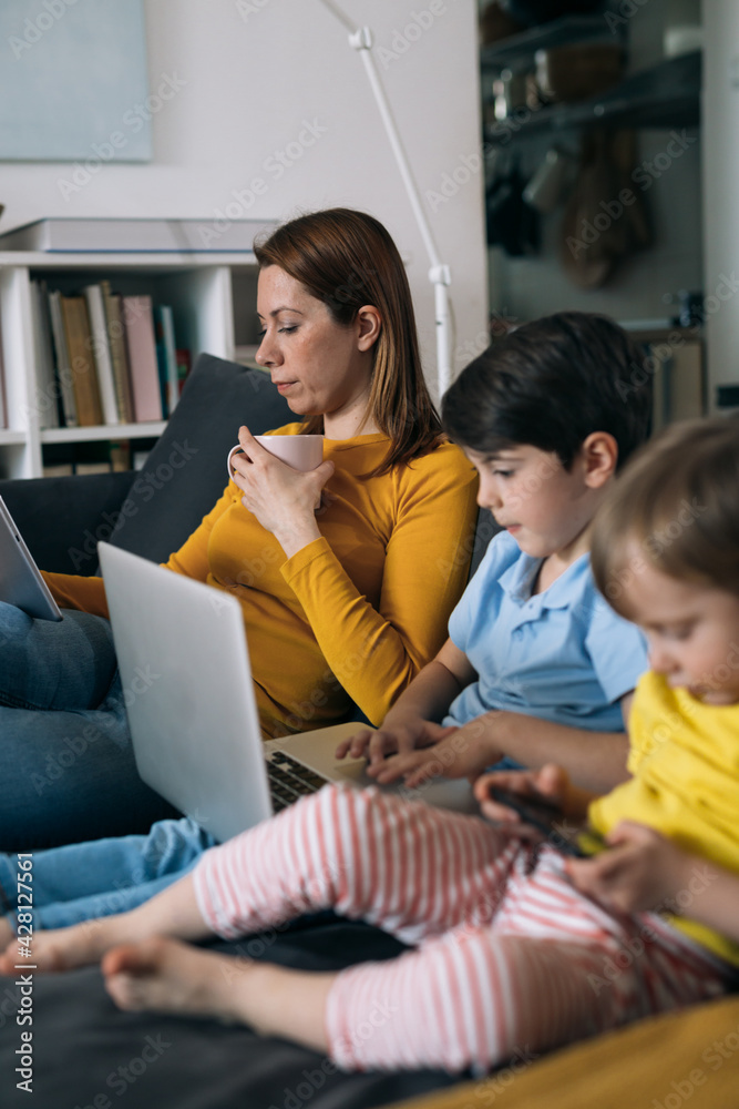 technology addicted asocial family sitting on sofa and using laptop, digital tablet and smartphone. technology addicted asocial family sitting on sofa and using laptop, digital tablet and smartphone.
