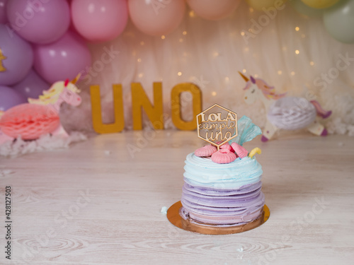 First birthday smashcake photo session with a rainbow of balloons and unicorns in a photo studio photo