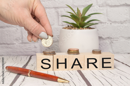 Share written on wooden dice, hand folding coins, the concept of profit and margin income