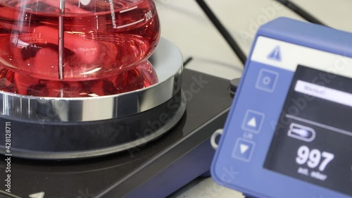 Stirring and mixing a red liquid in a laboratory flask by magnetic mixer