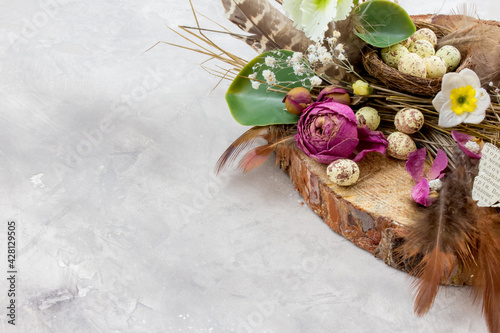 Easter composition with eggs, feathers and flowers on grey background