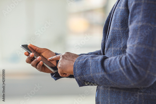 Close up of a business man using mobile smart phone, background for copy.. Using smart phone. Close-up image of male hands using smartphone, searching or social networks concept © Dragana Gordic