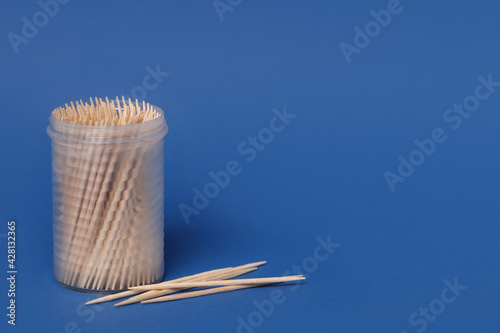 Wooden toothpicks and holder on blue background. Space for text photo