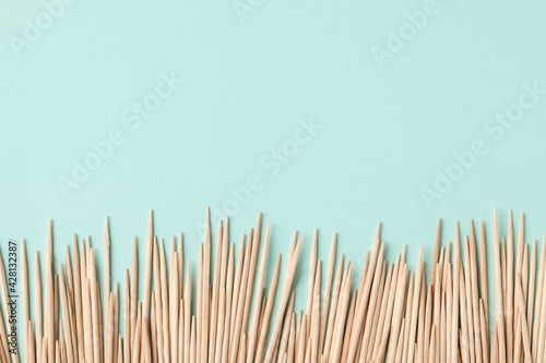 Wooden toothpicks on light blue background, flat lay. Space for text