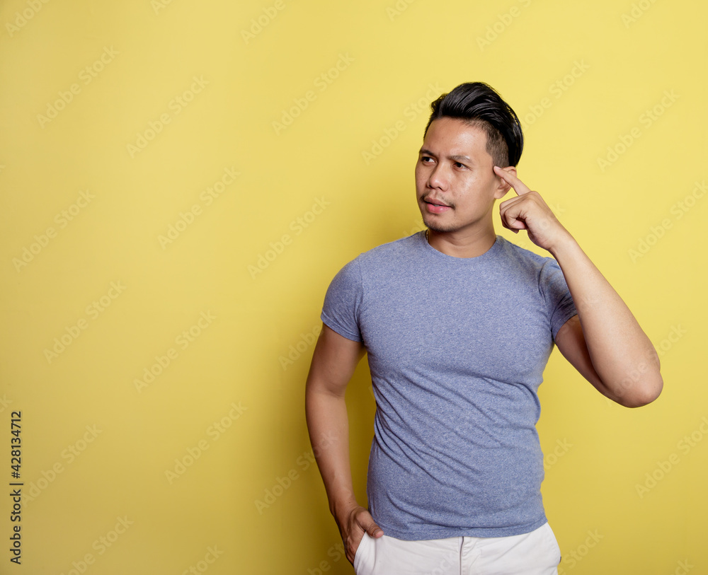 handsome man smile thingking idea with holding the head isolated on a yellow color background handsome man smile thingking idea with holding the head isolated on a yellow color background
