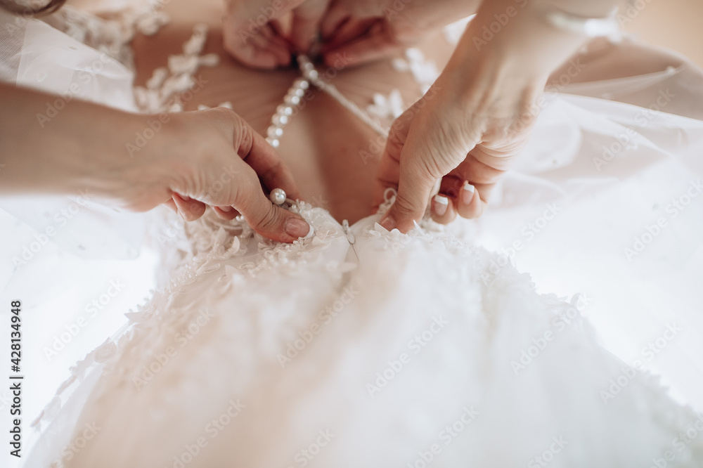gathering of the bride, buttoning up a wedding dress close-up, buttons and woman's hands, an unbuttoned dress gathering of the bride, buttoning up a wedding dress close-up, buttons and woman's hands, an unbuttoned dress