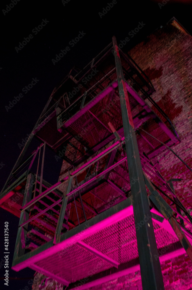 iron staircase on a brick wall in the evening, backlit iron staircase on a brick wall in the evening, backlit
