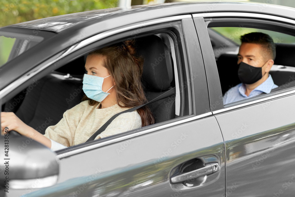 transportation, health and people concept - female driver driving car with male passenger wearing face protective medical mask for protection from virus disease transportation, health and people concept - female driver driving car with male passenger wearing face protective medical mask for protection from virus disease
