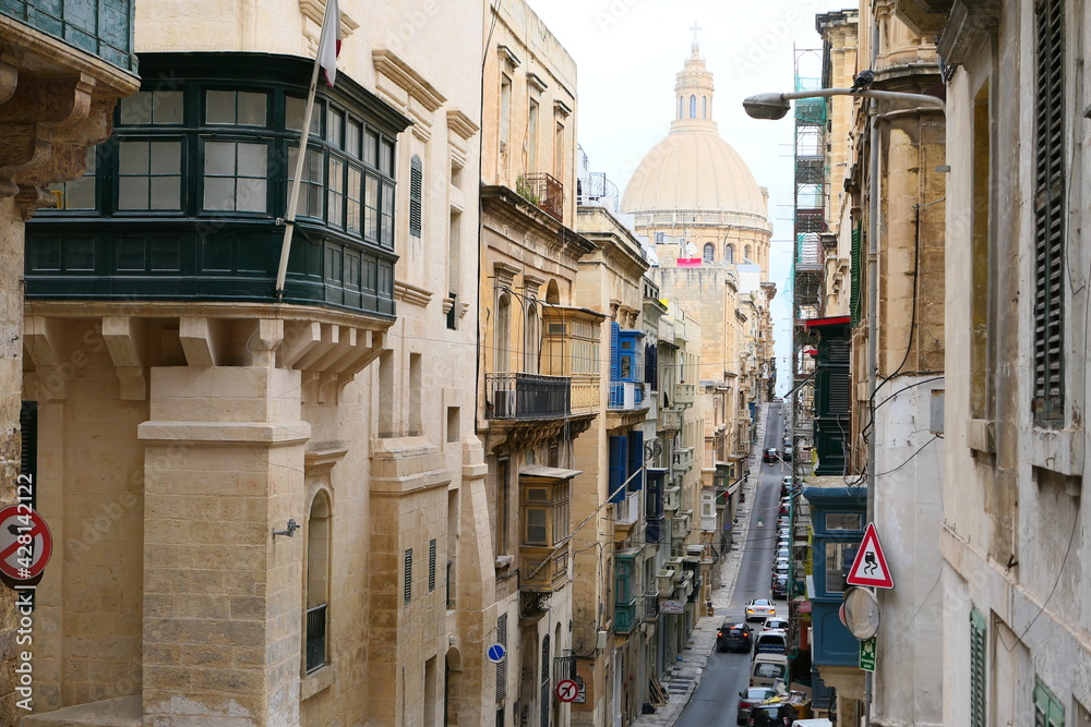 Valletta, Malta, March 17, 2021: St. Paul's Anglican Cathedral as seen from the top of the narrow Old Mint Street in Valletta with hanging balconies on either side.