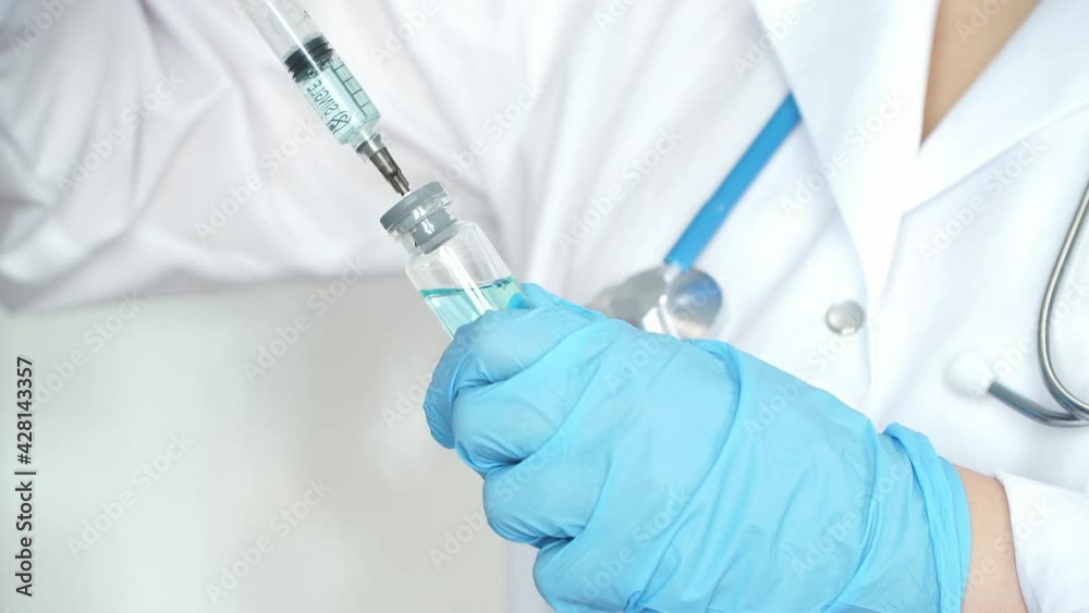 Close up of nurse hands in medical gloves fill syringe with drug on background of white coat. Ampoule with vaccine for covid-19. Coronavirus Close up of nurse hands in medical gloves fill syringe with drug on background of white coat. Ampoule with vaccine for covid-19. Coronavirus