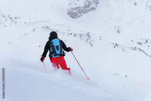 A young female skier rides a snowy mountainside in poor visibility. Bad weather skiing concept Back view