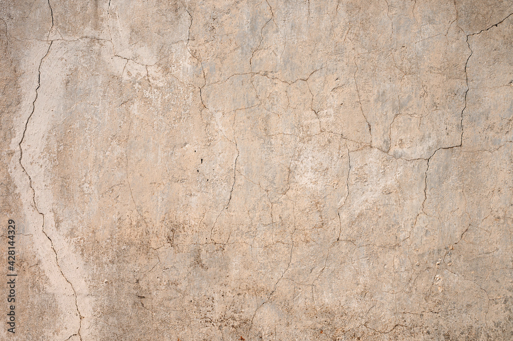 Grunge gray background of cracked peeling walls with peeled putty in beige tones.
