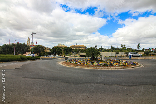 A floral covered roundabout looking towards the skyline of the town of Floriana on the Mediterranean island of Malta