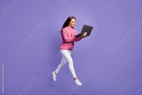 Profile photo of freelancer worker lady jump hold netbook go wear pink sweater pants shoes isolated purple background © deagreez