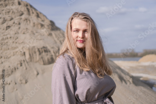Beauty portrait of a young blond girl in a vintage dress. She is posing on a sandy landscape. © Stock Rocket