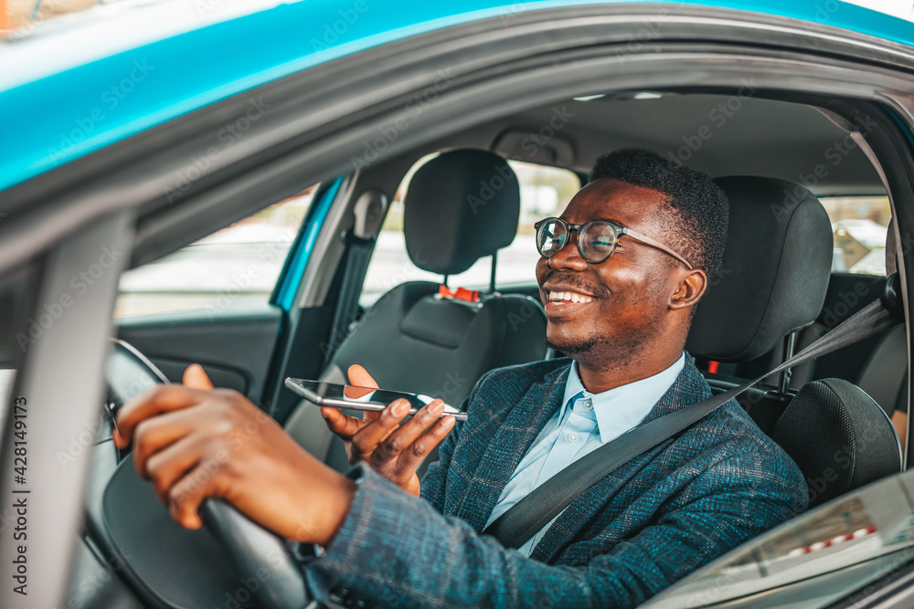 Close up of a handsome young businessman talking on mobile phone in his car. Man sitting in car and call. Young neglectful guy talking on his mobile phone while driving Close up of a handsome young businessman talking on mobile phone in his car. Man sitting in car and call. Young neglectful guy talking on his mobile phone while driving