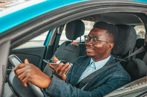 Calling by driving. Risky driver using phone while driving. Close up of a handsome young businessman talking on mobile phone in his car. Businessman Talking on the Phone while Driving a Car © Dragana Gordic