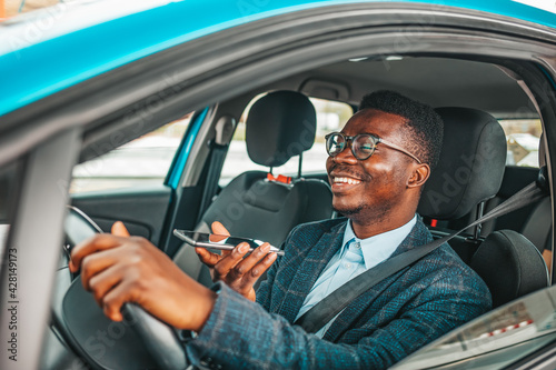 Close up of a handsome young businessman talking on mobile phone in his car. Man sitting in car and call. Young neglectful guy talking on his mobile phone while driving