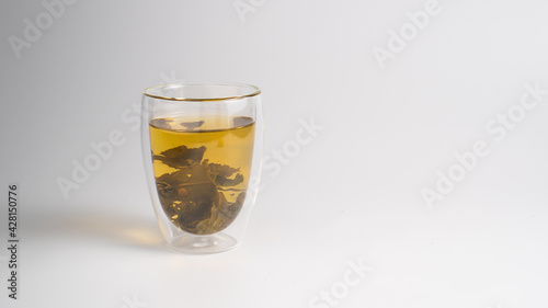 Green tea leaves in a transparent cup. Background with a cup of tea and copy space.