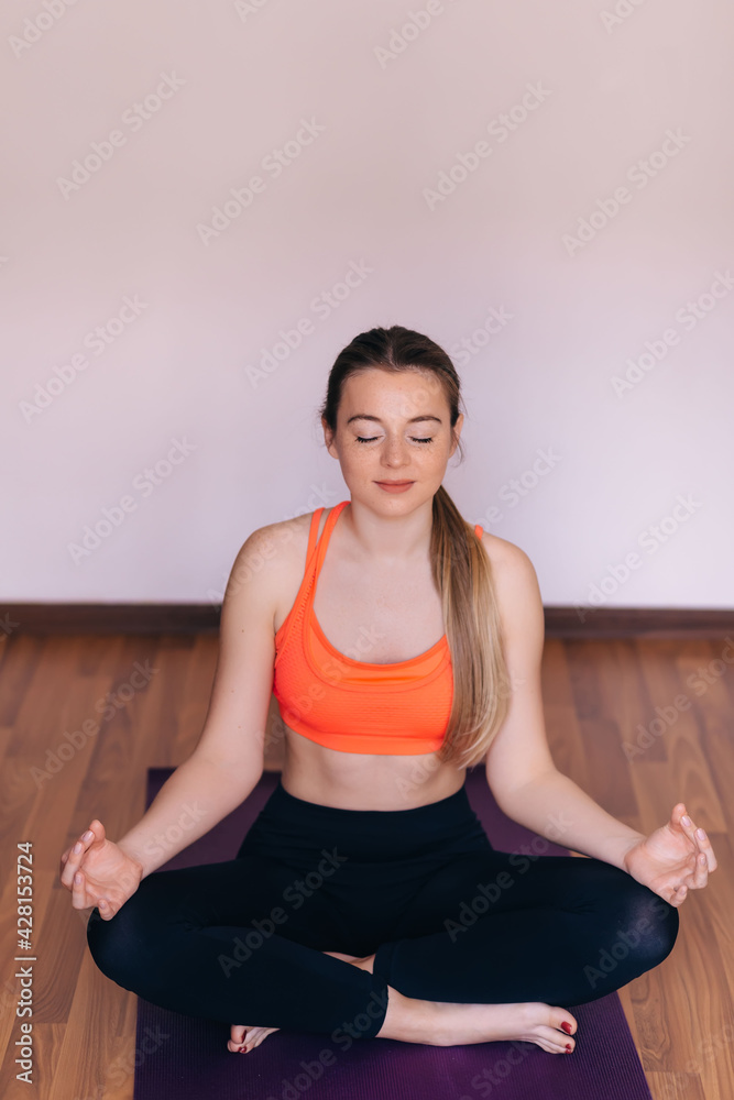 Pretty young woman wearing sportswear while doing meditation in