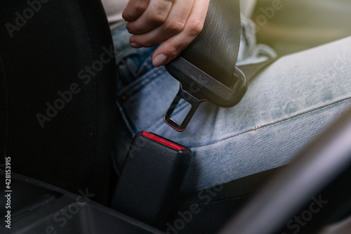 Close-up of car seat belt fastener. Woman s hand fastens the sea
