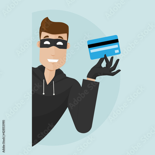 The thief peeks around the corner and holds a stolen credit card in his hand.